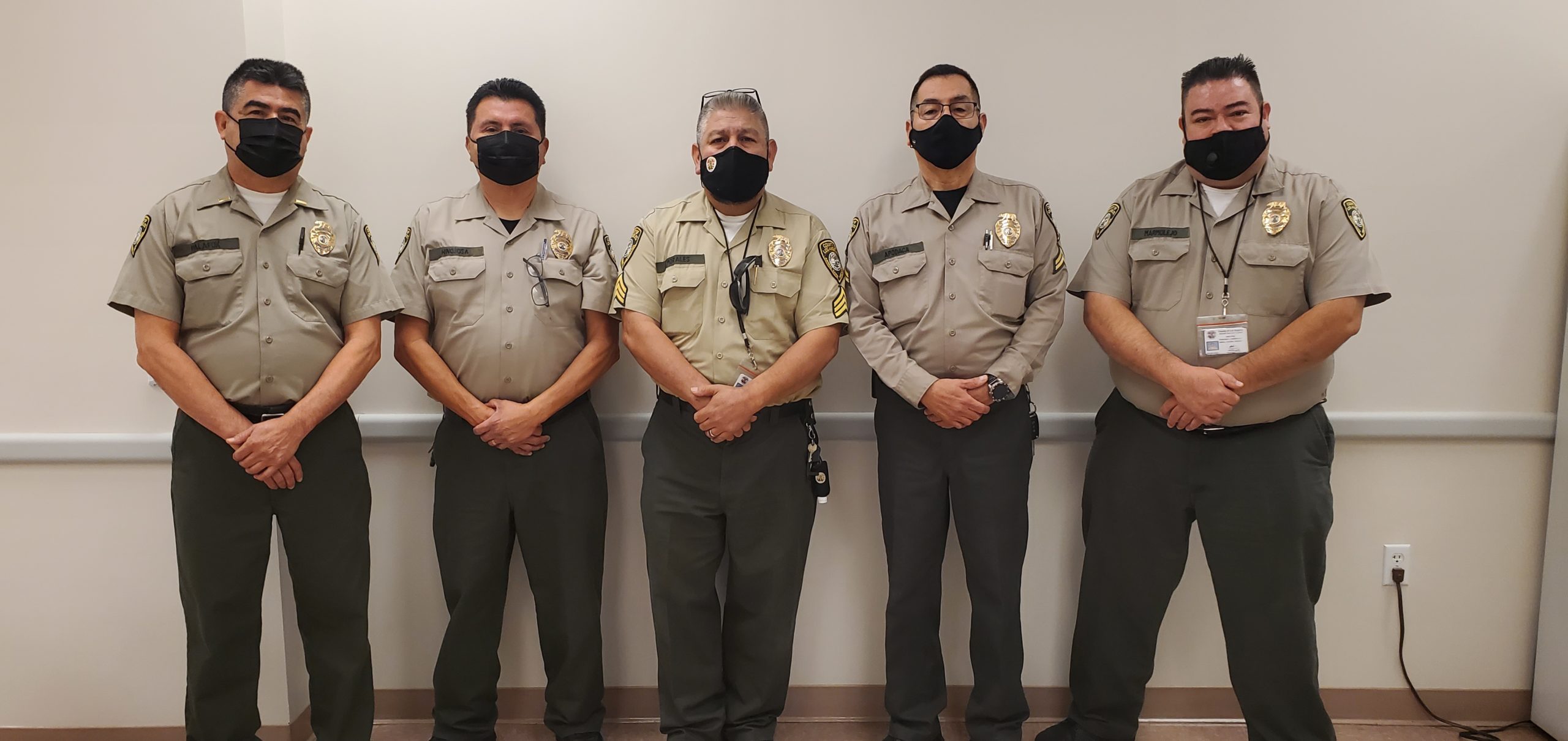 Five Animal Control officers from Business License Team with black masks on their face standing against the wall shoulder to shoulder
